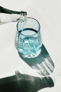 Person Pouring Water on Clear Drinking Glass
