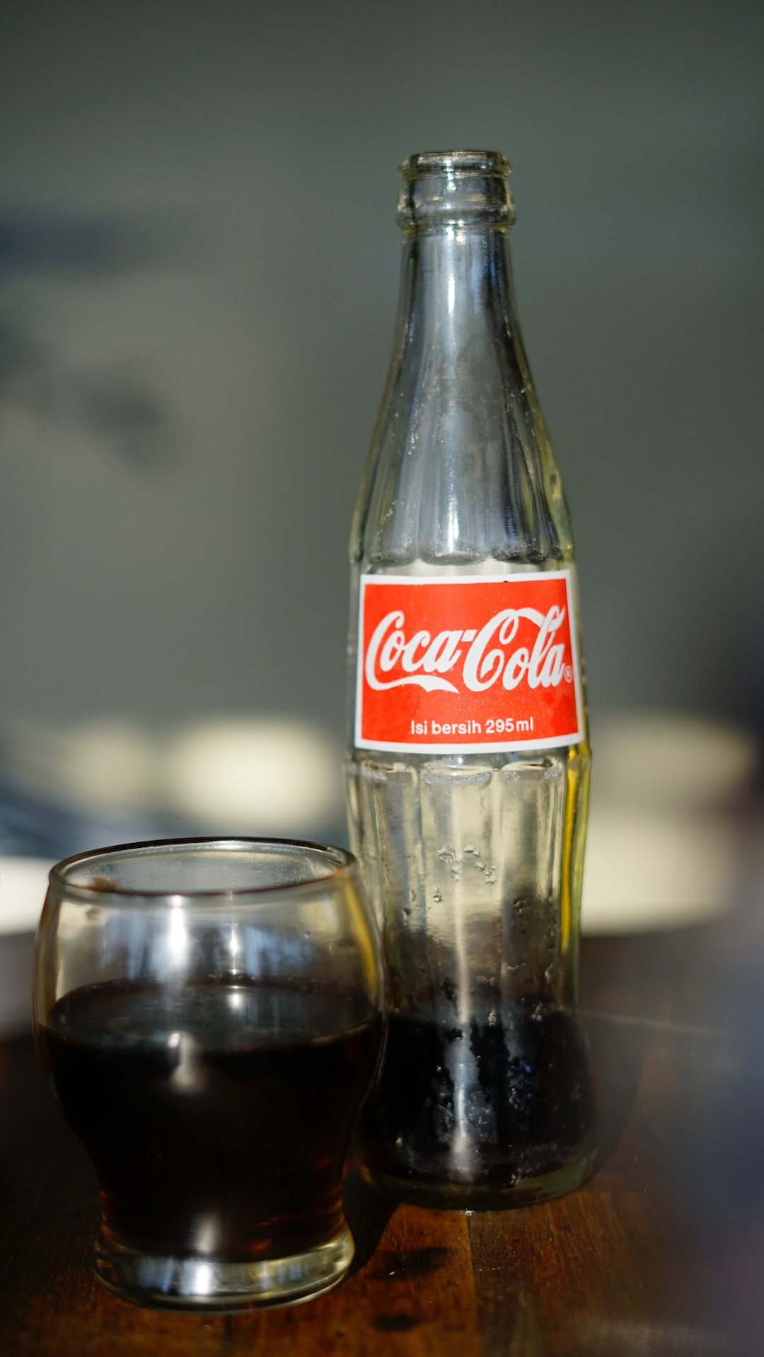 Coca-Cola soda bottle beside drinking glass